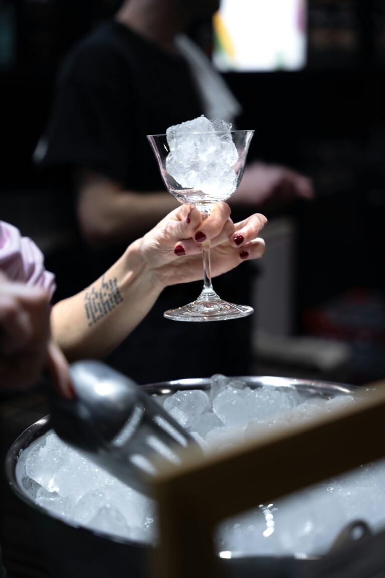 A close-up shot of a hand holding a cocktail glass with ice cubes in a Paris bar setting. Perfect for bar and nightlife themes.